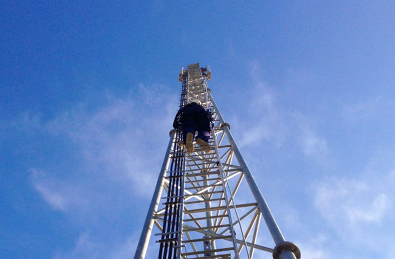 travailleur en hauteur montant sur un pylône telecom